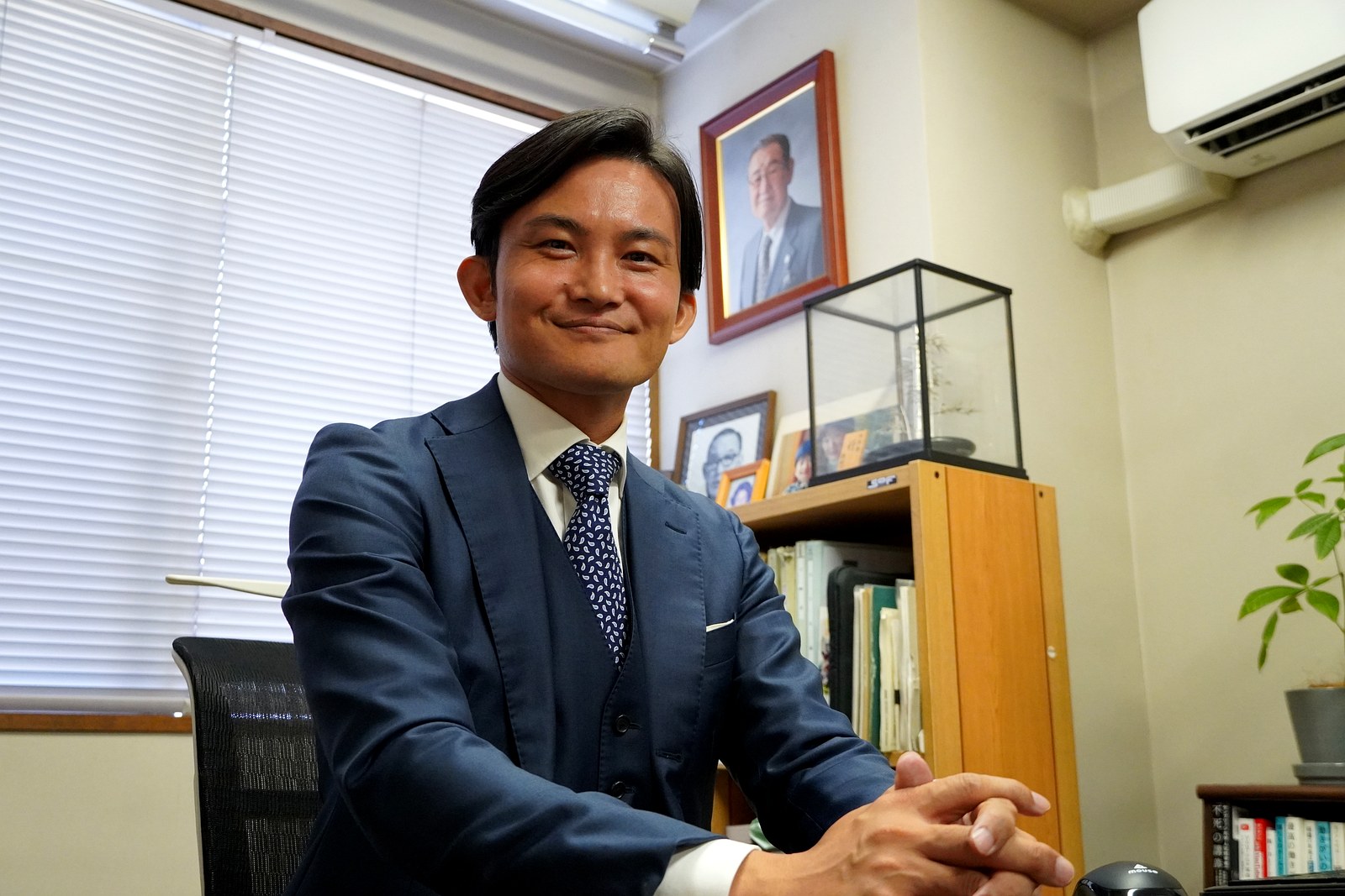 先代の肖像を背に社長室で語る平澤宏光社長