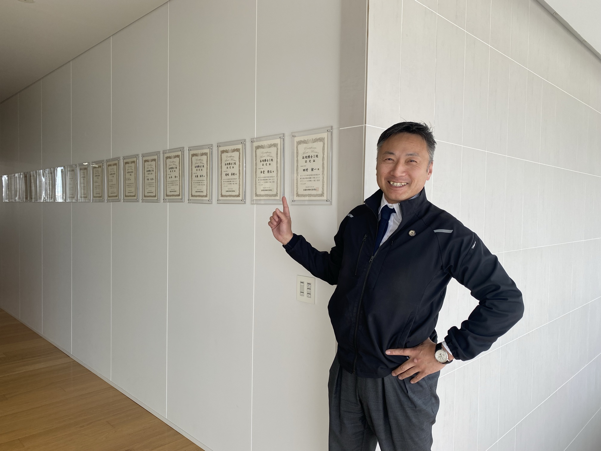 北一ミート株式会社 代表取締役 田村健一氏（お肉博士認定証の前で）
