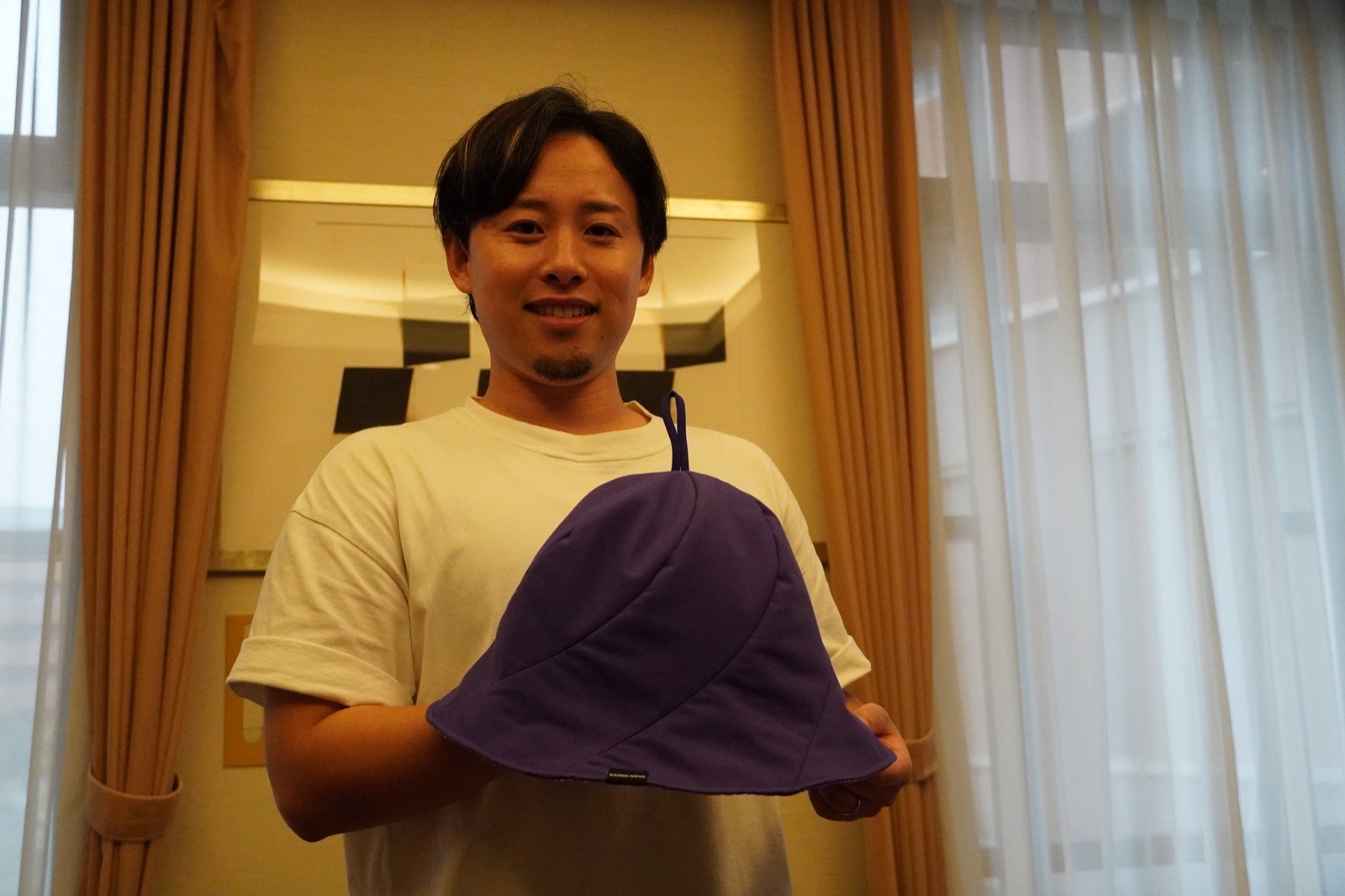 SAUNA NOVAのサウナハットを両手で持つ加納優誉氏