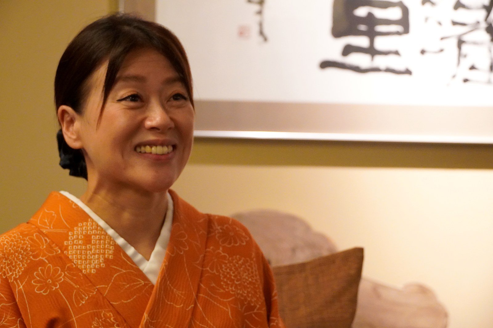 大松閣ロビーの「里」の書を背に、柔らかな笑顔を見せる柏木由香さん