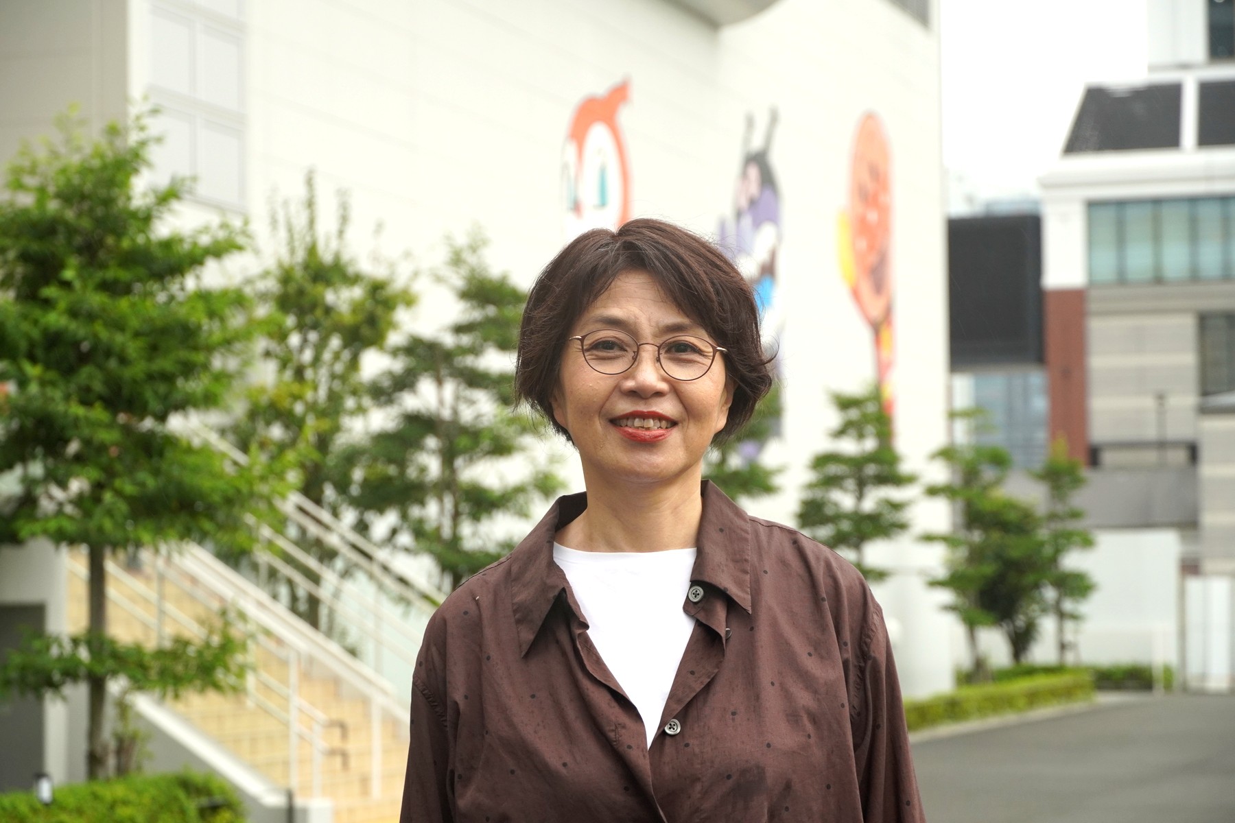 アンパンマンこどもミュージアムの壁画を背景にした三浦さん