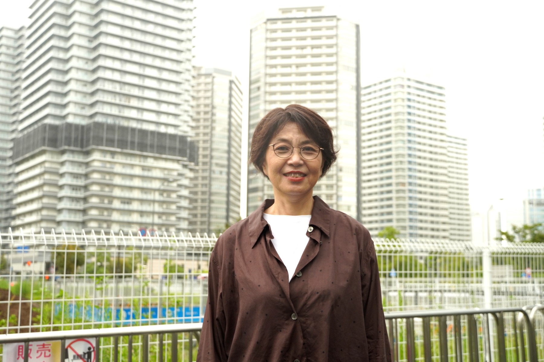 高層マンション街を背景にした三浦さん