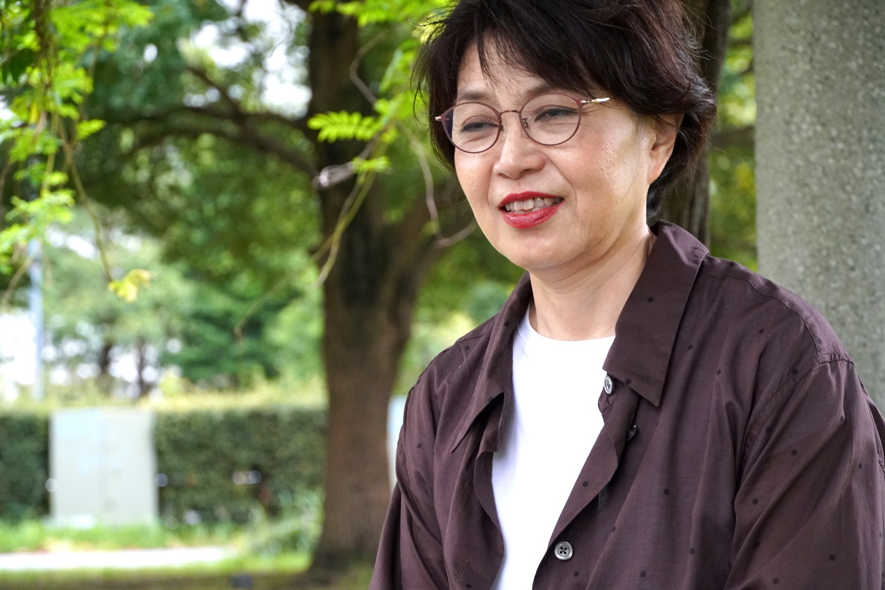 緑を背景に微笑む三浦さん