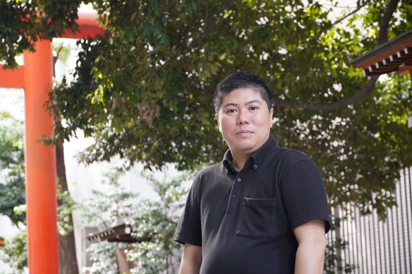 花園神社の木々の下に立つ渡邉朋宏氏