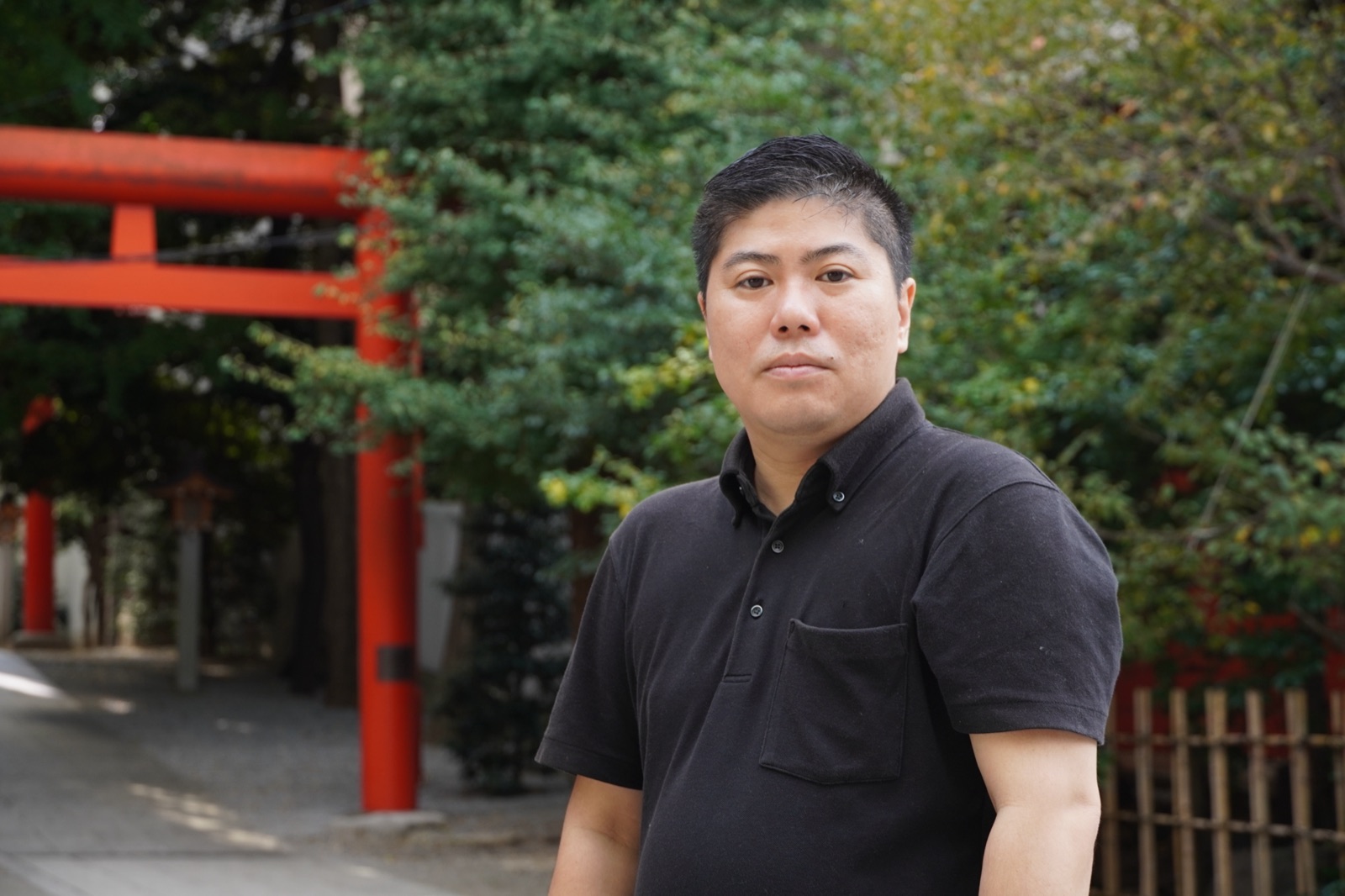朱色の鳥居の前に立つ渡邉朋宏氏